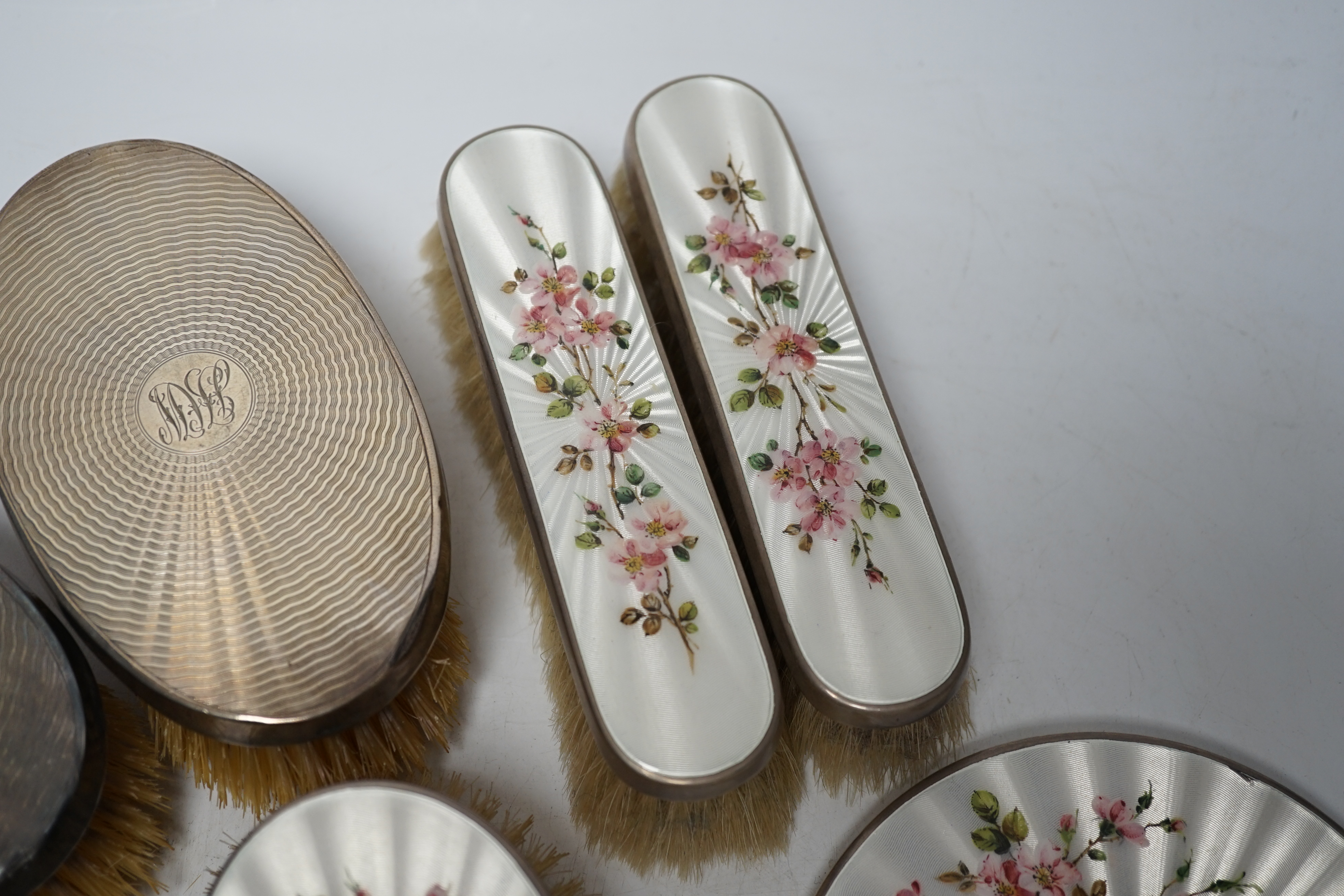 A George VI five piece silver and enamel mounted mirror and brush set, London, 1941 and a pair of silver mounted clothes brushes.